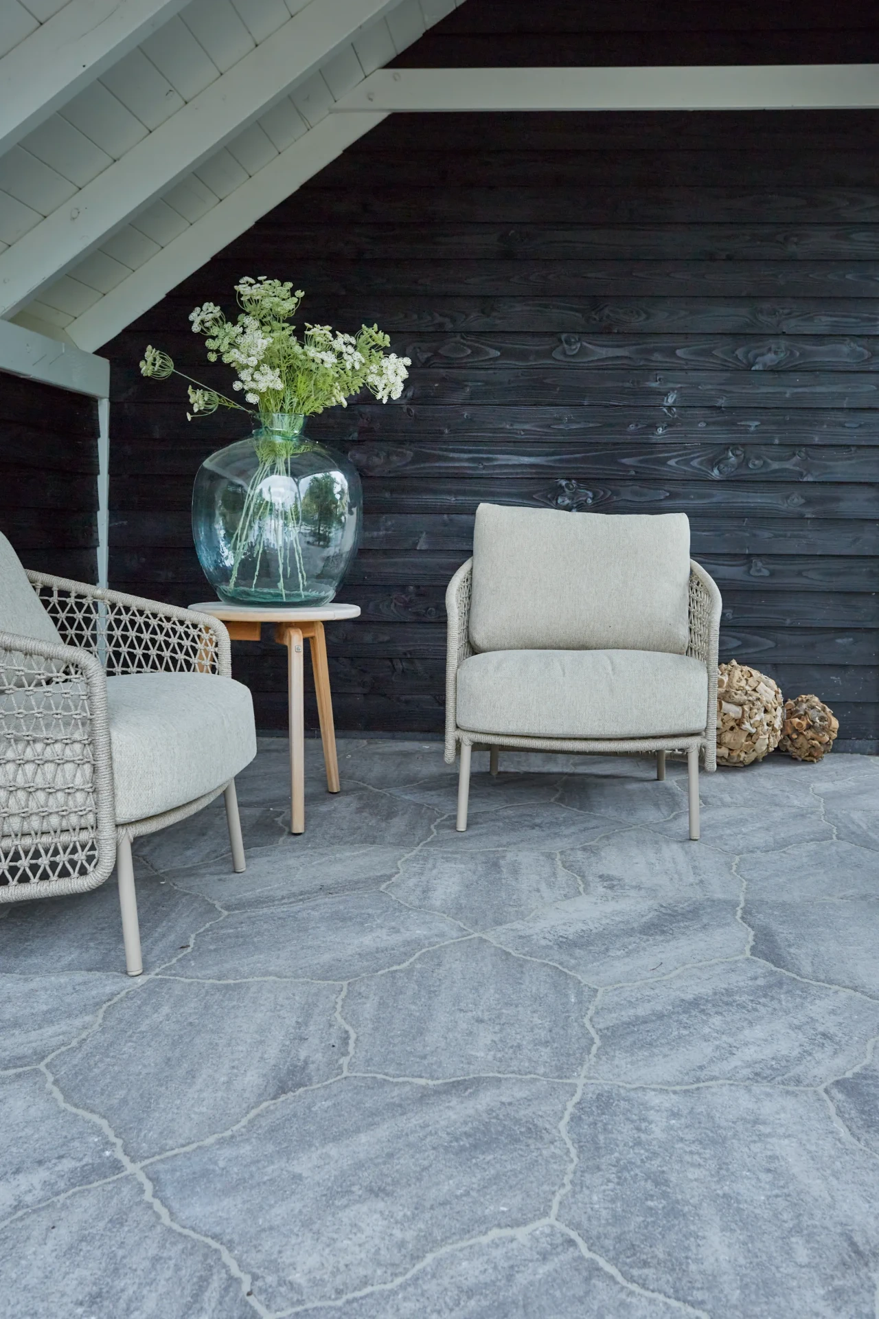 Knusse loungehoek met stoelen op een terras van natuursteen flagstones